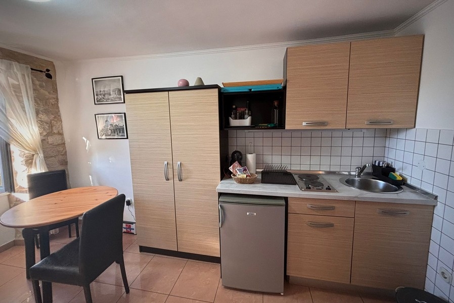 Vista interna di una piccola cucina di un immobile in Croazia con tavolo e armadi a muro