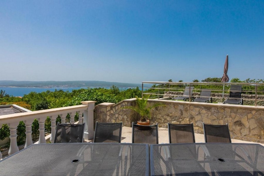 Terrazza di una casa plurifamiliare in Croazia con tavolo e sedie, vista mare sullo sfondo