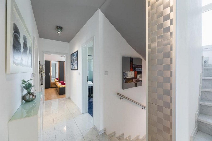Ingresso e corridoio di una casa plurifamiliare in Croazia con vista mare, con piastrelle lucide a pavimento, vano scale e decorazioni alle pareti