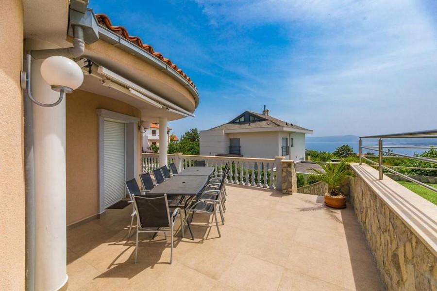 Ampia terrazza di una casa plurifamiliare in Croazia con lungo tavolo e sedie, vista mare