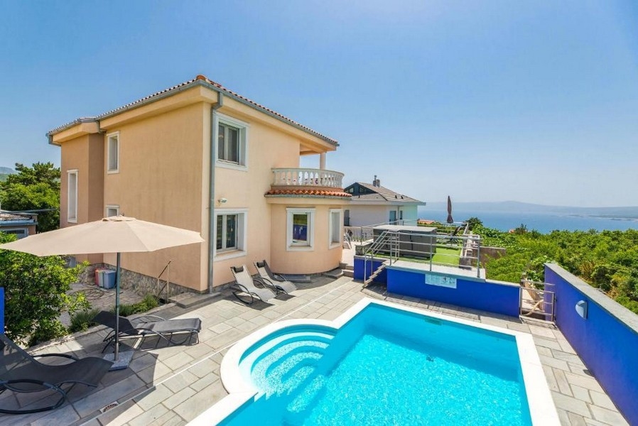 Retro di una casa plurifamiliare in Croazia con piscina e sedie a sdraio, vista mare