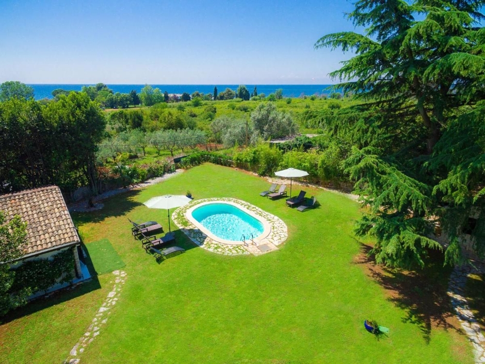 Ripresa aerea di un giardino verde con una piscina a forma di cuore, ideale per immobili in Croazia