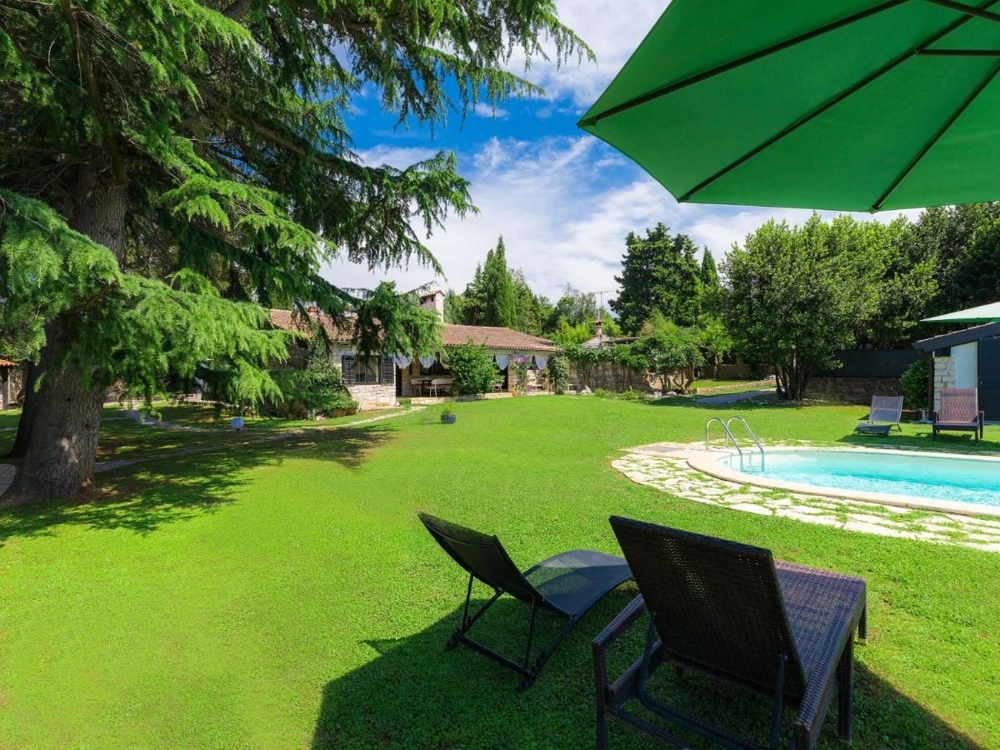 Giardino idilliaco con sdraio e vista su un complesso di edifici in pietra, rappresentativo di immobili in Croazia