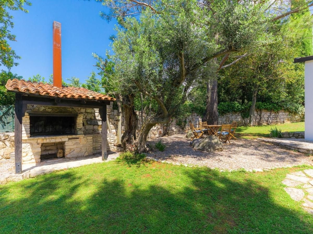 Rustica area barbecue all'aperto con posti a sedere sotto gli ulivi, caratteristica di immobili in Croazia