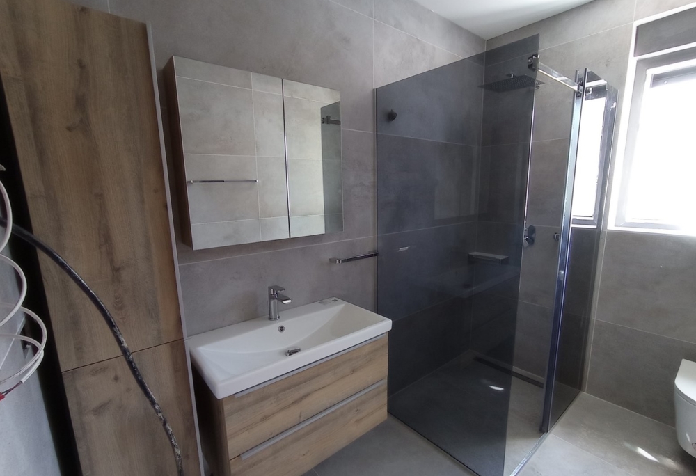 Bagno moderno con doccia walk-in in un immobile in Croazia, mobile a specchio ed elementi in legno nel design.