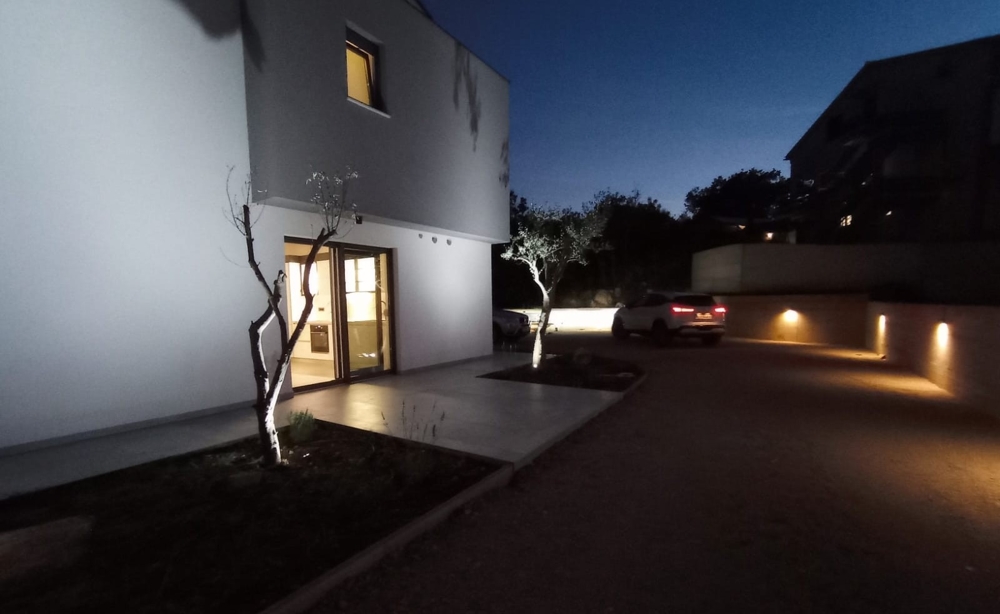Ripresa notturna di un immobile in Croazia con illuminazione esterna e auto parcheggiata nel cortile.