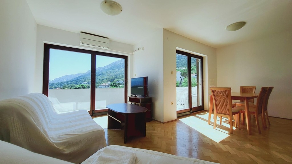 Soggiorno con divano, tavolo da pranzo e porte-finestre sul balcone