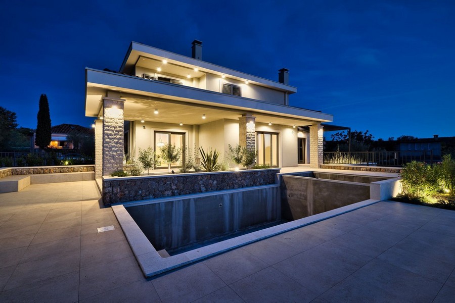 Villa illuminata con piscina e zoccolo in pietra naturale di sera