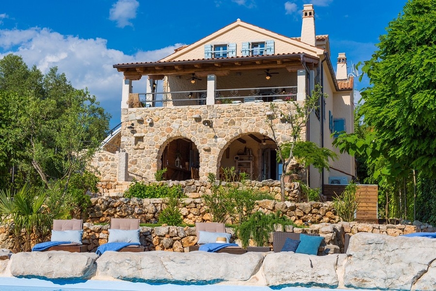Vista frontale di una villa mediterranea con piscina e archi in pietra, rappresentativa dell'immobile sull'isola di Krk.