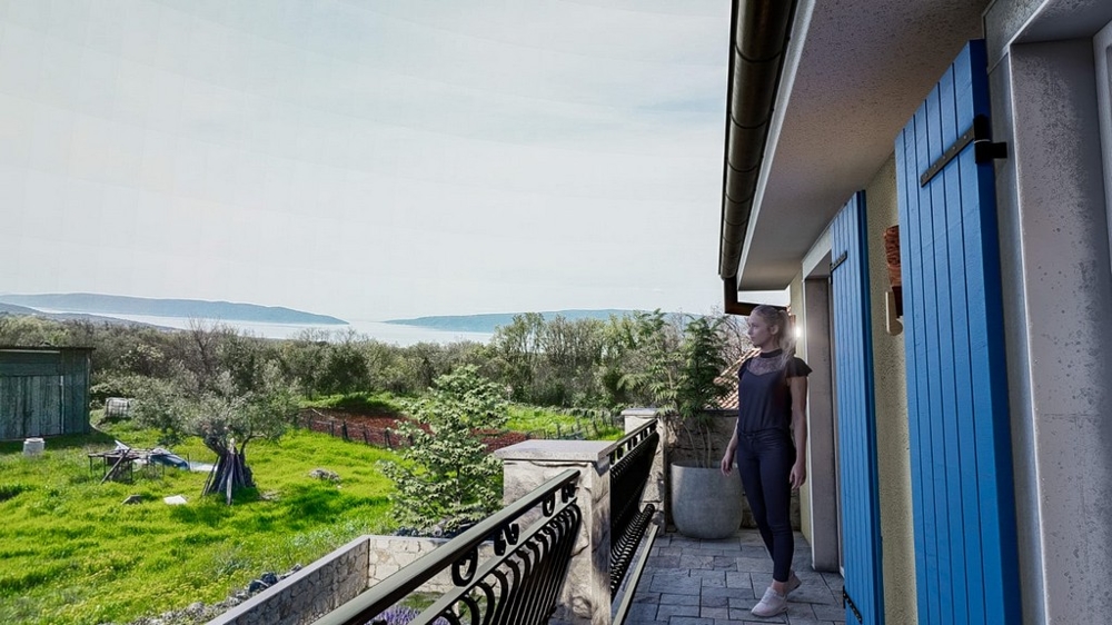 Donna gode la vista mare da un balcone di una villa mediterranea sull'isola di Krk