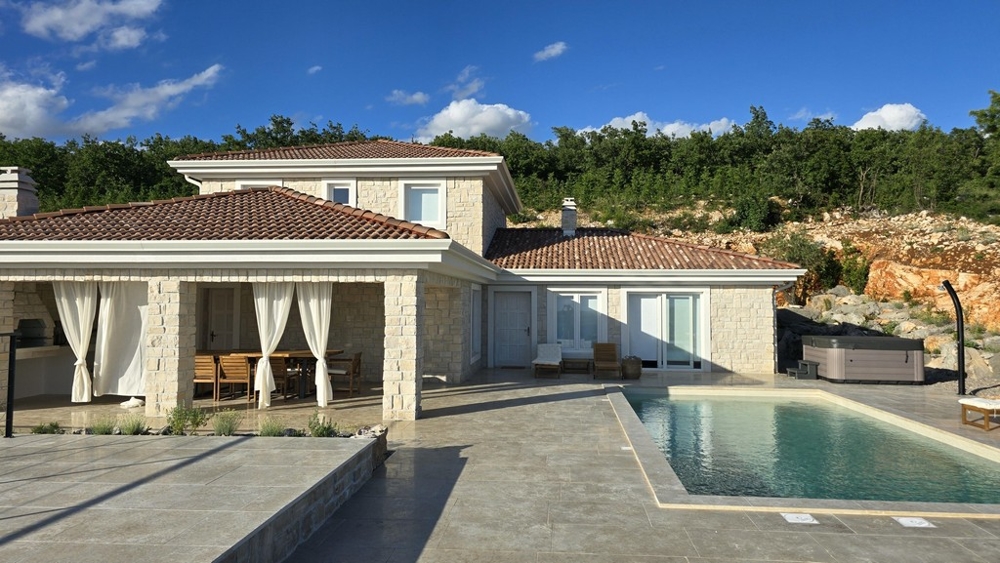 Casa in pietra con tende alla loggia e piscina davanti