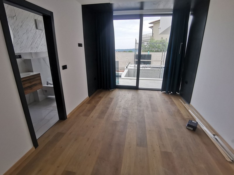 Camera da letto con pavimento in legno e passaggio verso il bagno in marmo