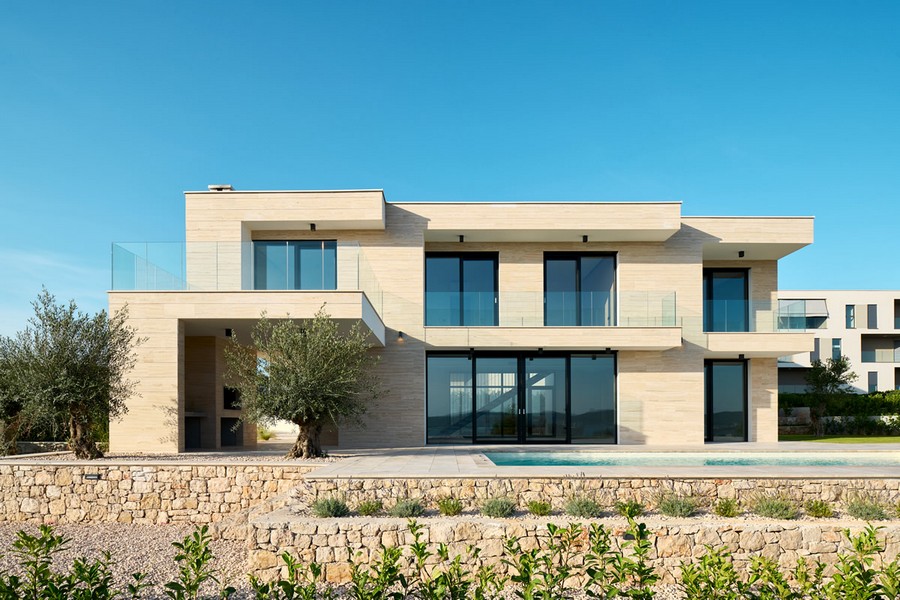 Villa con facciata in pietra chiara e ulivo accanto alla piscina