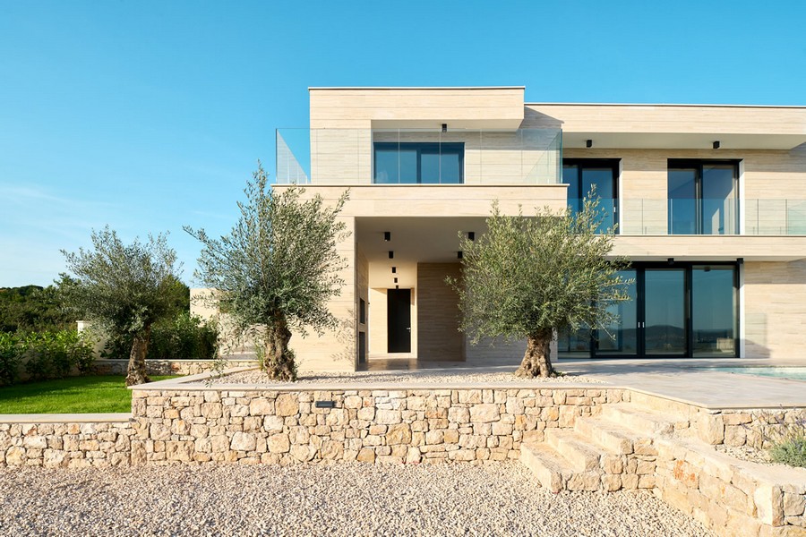 Villa con facciata in pietra e ulivi sopra il muro a secco