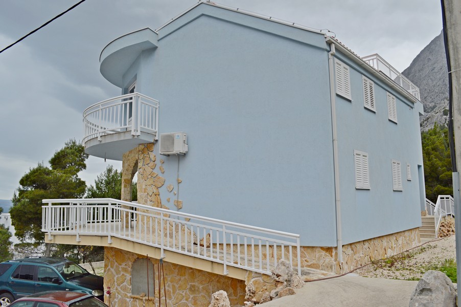 Casa blu con muro in pietra e balcone