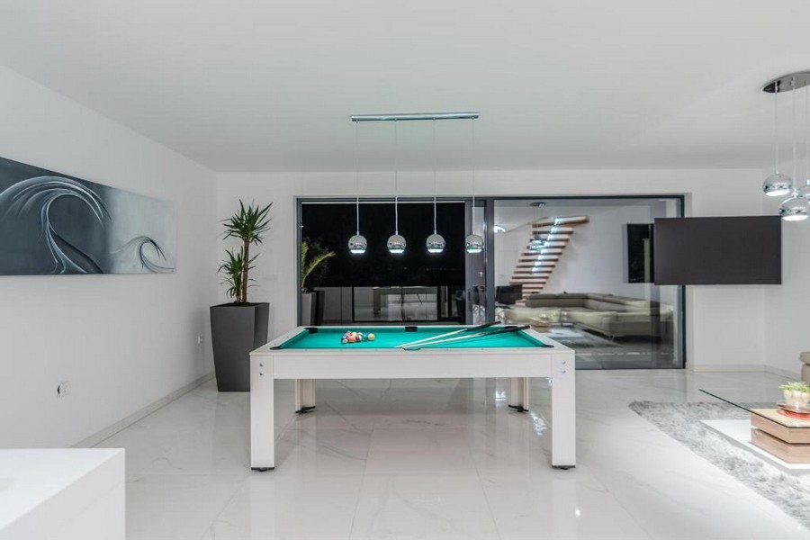 Sala relax con tavolo da biliardo ed eleganti corpi illuminanti