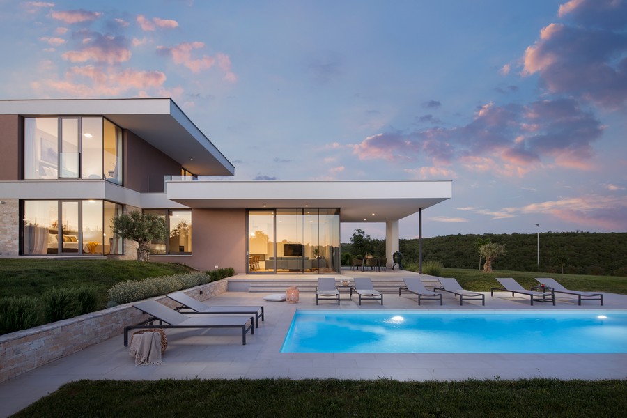Villa con piscina e lettini sotto nuvole rosa della sera
