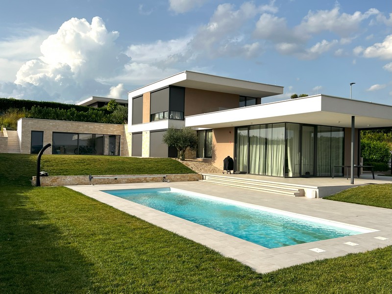 Lunga piscina davanti alla villa sotto nuvole cumuliformi