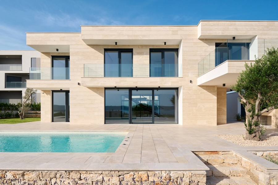 Villa con facciata in pietra chiara e piscina dietro il muro a secco