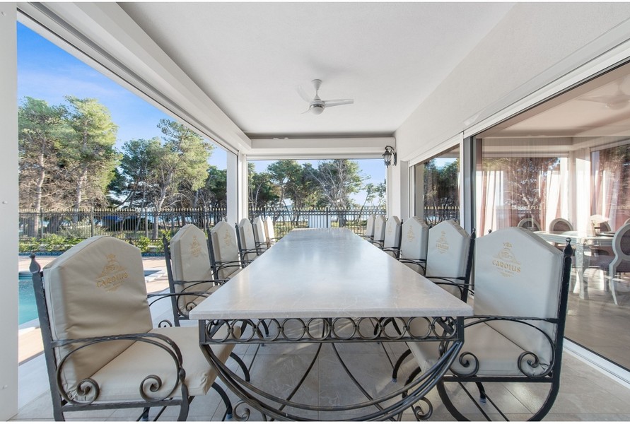 Zona pranzo coperta della villa H3042 con un grande tavolo e sedie eleganti