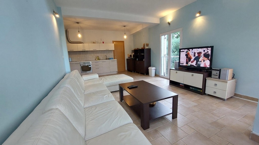 Zona giorno con divano bianco, tavolino e televisore in una casa in Croazia