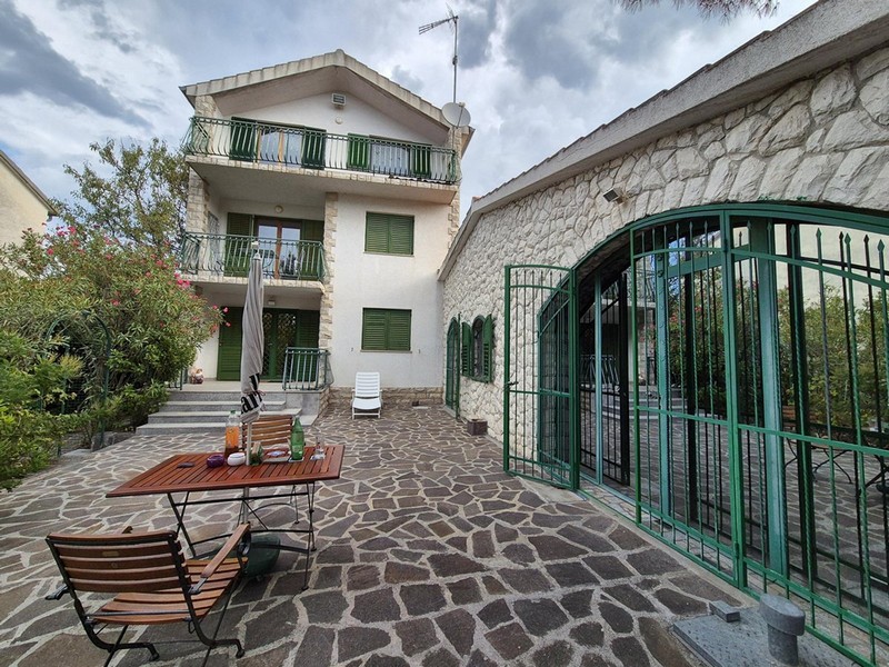 Casa con persiane verdi e tavolo da giardino sul cortile in pietra