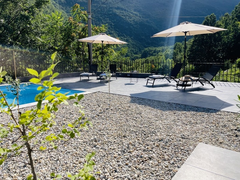 Solarium in piscina con lettini e ombrelloni, circondato dal verde della natura