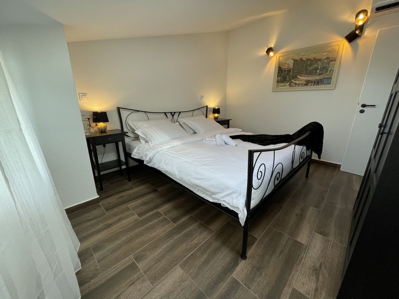 Camera da letto con letto in ferro battuto, pavimento in legno e applique, con vista laterale su un dipinto