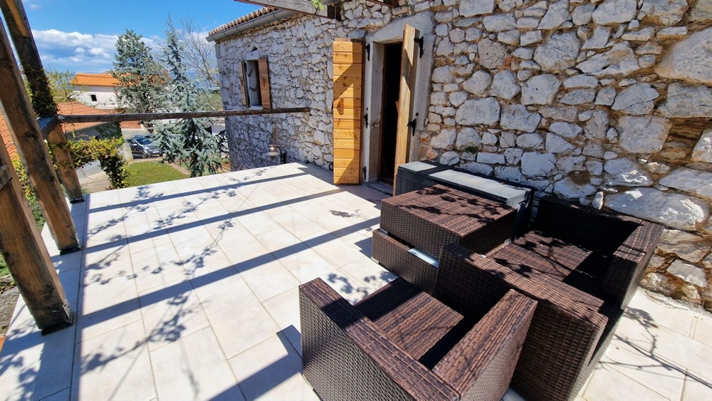 Solarium con sedute davanti a una casa in pietra rustica.