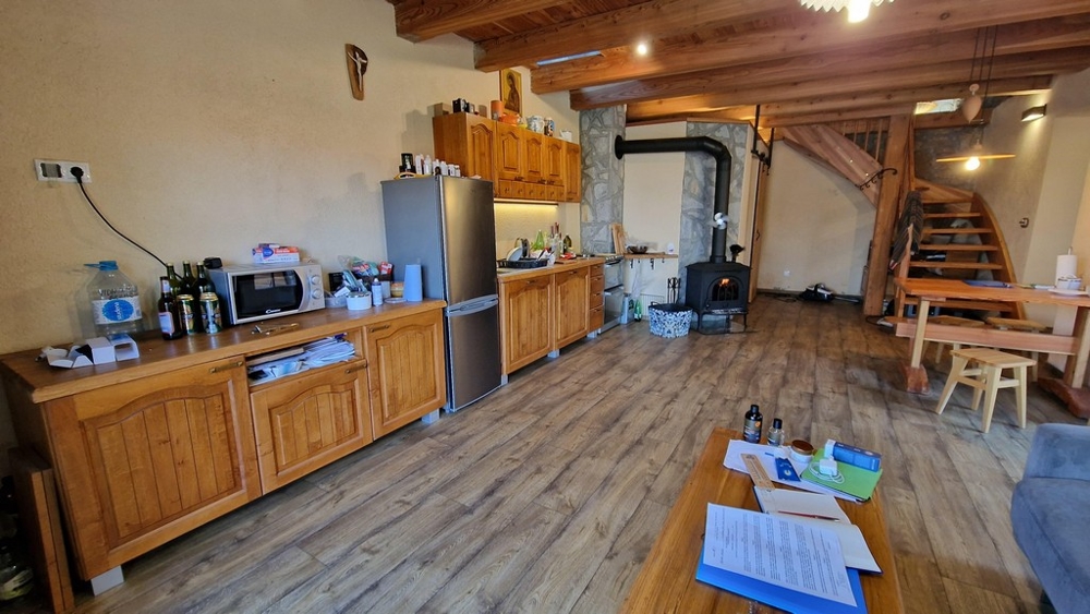 Cucina con armadi in legno, frigorifero e tavolo da pranzo in stile rustico.