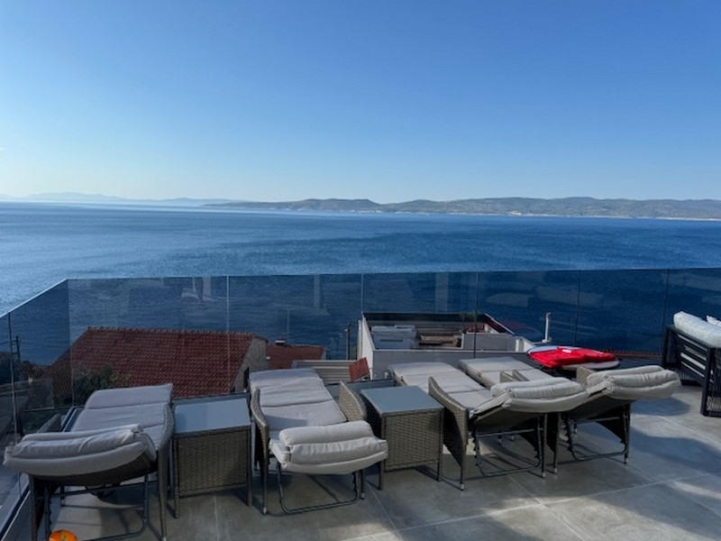Terrazza sul tetto con lettini e parapetto in vetro sopra il mare