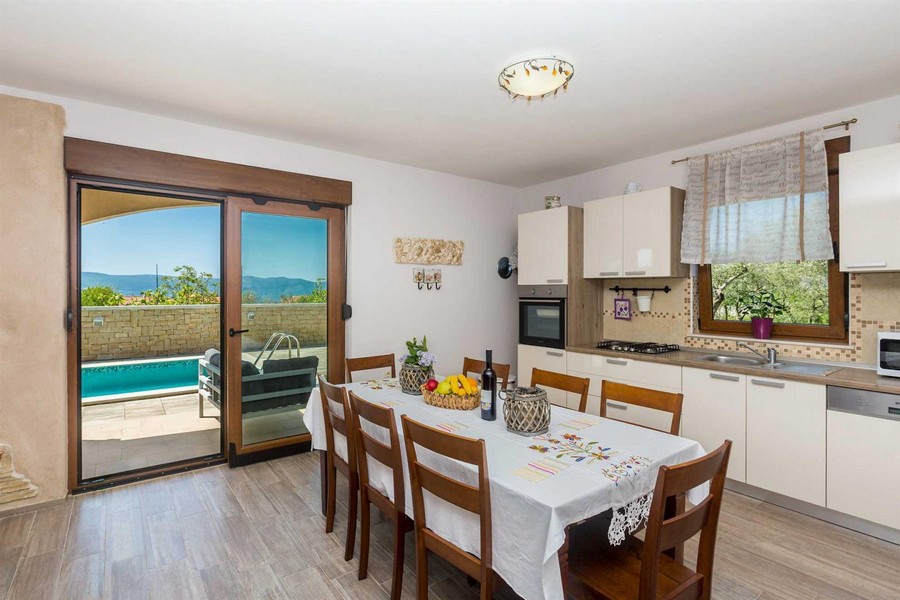 Zona pranzo e cucina funzionale, con vista sulla piscina dalla terrazza.