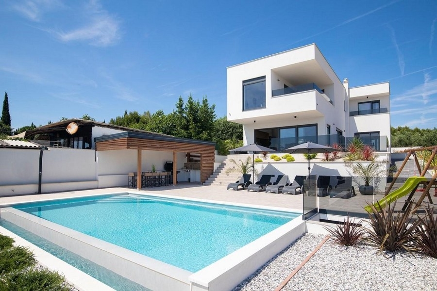 Villa bianca con piscina e cucina estiva sotto tettoia in legno