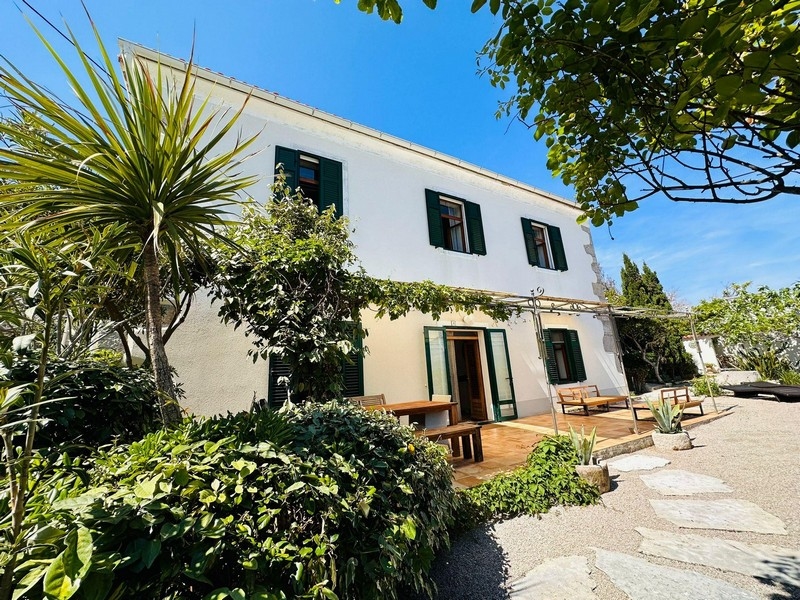 Casa in pietra bianca con persiane verdi nel giardino