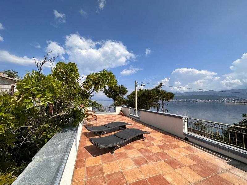 Terrazza con lettini e ringhiera in ferro battuto sopra la baia