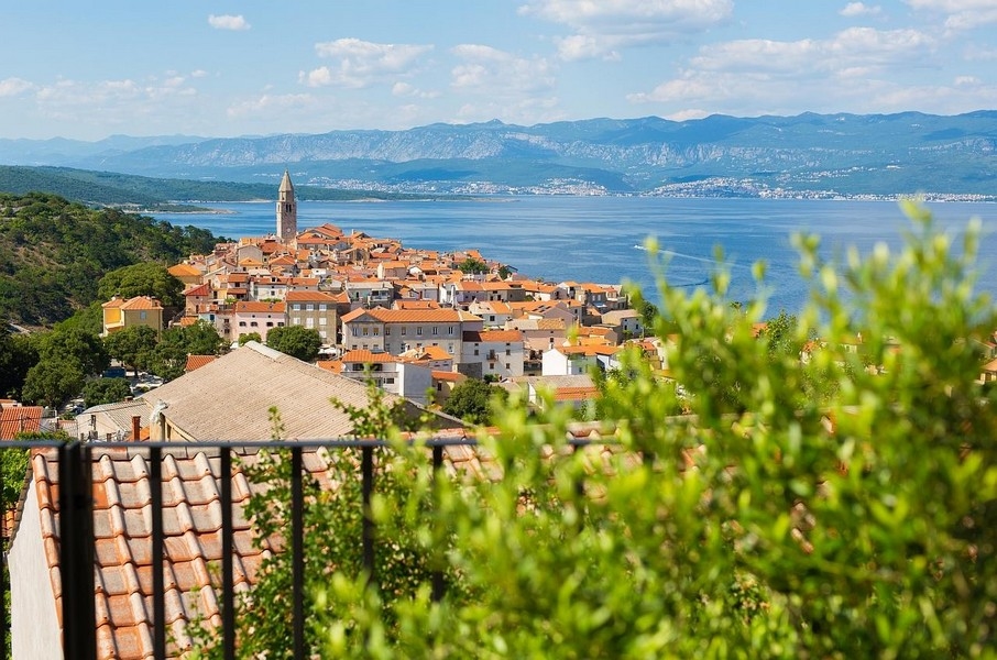 Vista sul paese con campanile, sulla baia e sui monti