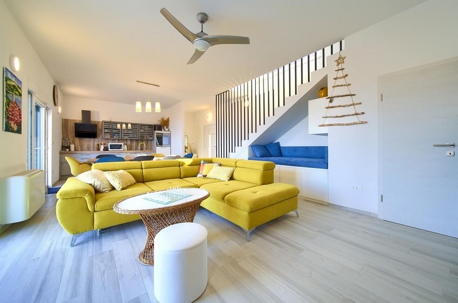 Ampio soggiorno con divano giallo, zona pranzo e cucina integrate, design moderno aperto