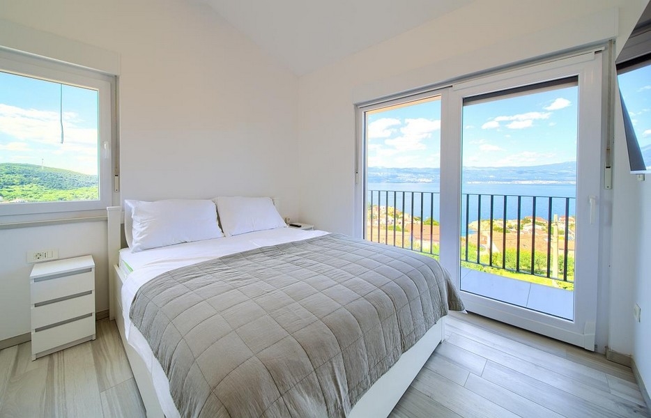 Camera da letto con letto matrimoniale e porte-finestre sul balcone, splendida vista mare sullo sfondo