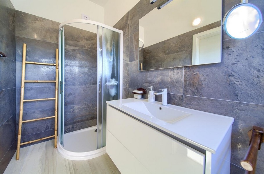 Bagno moderno con doccia, piastrelle grigie alle pareti e lavabo bianco