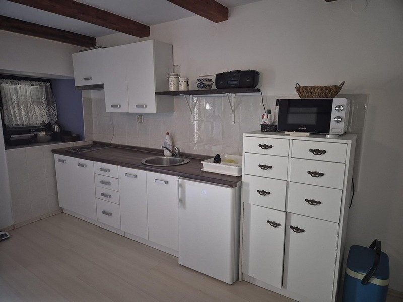 Cucina bianca moderna con piccoli armadi e scaffali.