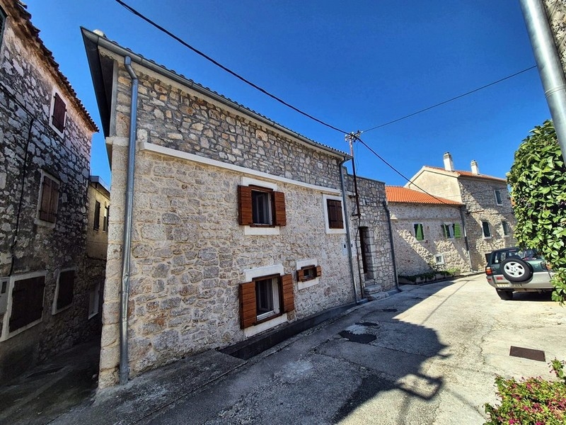 Casa in pietra con persiane in legno nella stretta strada del paese
