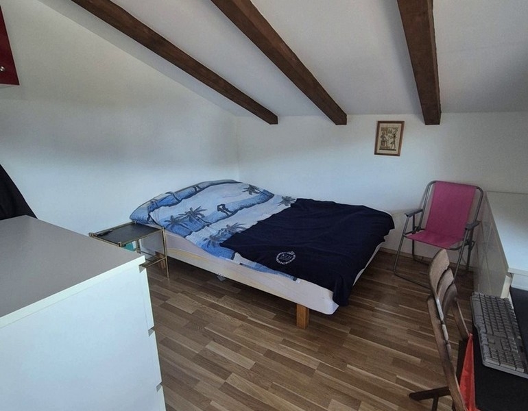 Camera da letto nel sottotetto con travi in legno e letto matrimoniale.