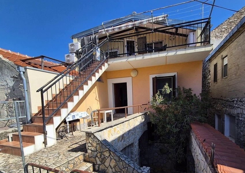 Vista posteriore della casa in pietra mediterranea con scala esterna e terrazza.
