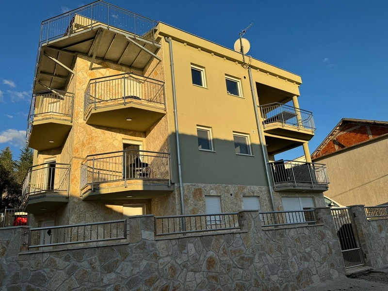Casa gialla con balconi e scala esterna nella luce della sera