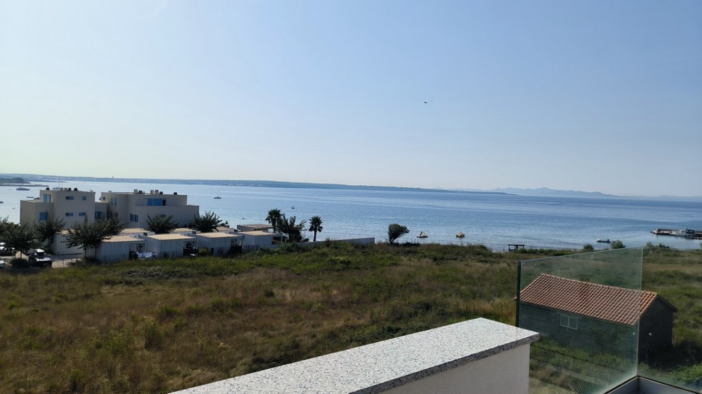 Vista mare dalla terrazza con case adiacenti e natura.