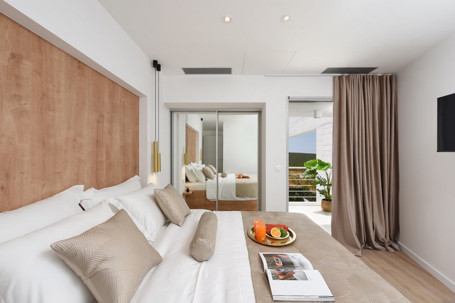 Camera da letto luminosa con accesso al balcone, decorazioni in toni di bianco e legno.