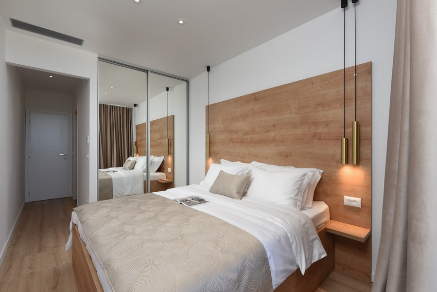 Camera da letto accogliente con decorazioni in legno, armadio a specchio e accesso diretto al balcone.