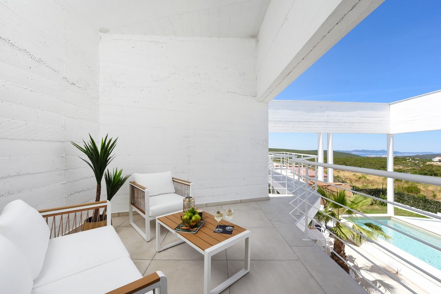 Terrazza coperta con zona seduta e vista sulla piscina e sui dintorni.