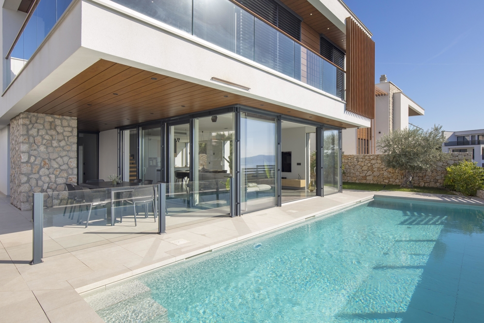 Porte a vetri pieghevoli verso la piscina sotto il soffitto in legno
