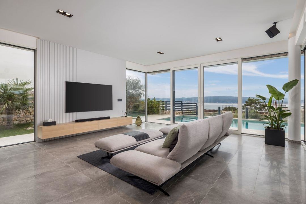 Soggiorno con parete TV e vista su piscina e mare